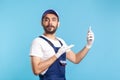 Surprised workman in overalls pointing mobile phone and looking amazed, shocked by online purchase order app