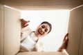 Surprised young asian woman unpacking. Opening carton box and looking inside Royalty Free Stock Photo