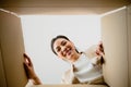 Surprised young asian woman unpacking. Opening carton box and looking inside Royalty Free Stock Photo