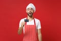 Surprised young bearded male chef cook or baker man in striped apron white t-shirt toque chefs hat isolated on red wall Royalty Free Stock Photo