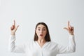 Surprised young beautiful brunette businesswoman smiling looking at camera pointing fingers up over white background. Royalty Free Stock Photo