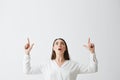 Surprised young beautiful brunette businesswoman smiling looking pointing fingers up over white background. Royalty Free Stock Photo