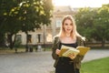 Surprised young beautiful female student posing in the college park outdoors holding books and notebooks. Attractive cute student Royalty Free Stock Photo