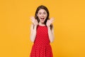 Surprised young brunette woman girl in red summer dress posing isolated on yellow wall background studio portrait Royalty Free Stock Photo