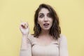 Surprised young brunette woman showing index finger up. Yellow background Royalty Free Stock Photo