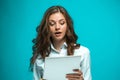 Surprised young business woman with pen and tablet for notes on blue background Royalty Free Stock Photo