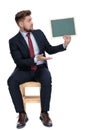 Surprised young businessman holding blackboard in studio