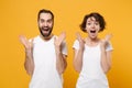 Surprised young couple friends bearded guy girl in white blank empty t-shirts isolated on yellow orange background Royalty Free Stock Photo