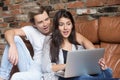 Surprised couple looking at laptop amazed by unbelievable online