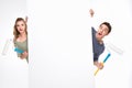 Surprised young couple with paint rollers and blank card looking at camera Royalty Free Stock Photo