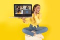 A surprised young woman in a yellow shirt and jeans sits cross-legged