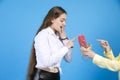 Surprised young female covering mouth with hand, while touching cactus, given by anonymous hands.