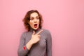 Surprised young girl in casual clothes and red curly hair shows pointing finger at copy space. Cute emotional lady showing thumbs Royalty Free Stock Photo