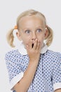 Surprised young girl covering mouth with her hand over white background Royalty Free Stock Photo