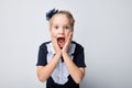 Surprised young girl with hands on cheeks against a gray background, expressing shock and amazement Royalty Free Stock Photo