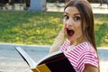 Surprised young girl reading a book outside Royalty Free Stock Photo