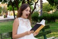 Surprised young girl with a wide opened mouth is reading a book in the park Royalty Free Stock Photo