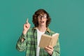 Surprised young guy reading book and pointing up on turquoise background Royalty Free Stock Photo