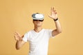 Surprised young male student in white t-shirt and vr spectacle moves hands, manipulating gestures