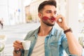 Surprised man drinking coffee outdoor takes sunglasses off Royalty Free Stock Photo