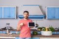 Surprised young man standing in kitchen and pointing at tablet, looking at camera with amazement Royalty Free Stock Photo