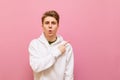 Surprised young man in white casual clothes looks into the camera and points his finger away at copy space isolated on pink. Guy Royalty Free Stock Photo