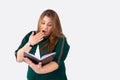 Surprised young overweight woman, gesturing surprise, reading a exciting book while sitting at the library, grey Royalty Free Stock Photo