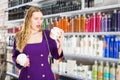 surprised young woman choosing hair care products at cosmetics store Royalty Free Stock Photo