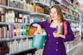 surprised young woman choosing hair care products at cosmetics store Royalty Free Stock Photo