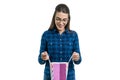 Surprised young woman in glasses and casual shirt looks in shopping bag, white background Royalty Free Stock Photo