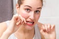 Surprised young woman holding dental floss caring and cleaning teeth Royalty Free Stock Photo