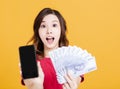 Surprised young woman holding mobile phone and money Royalty Free Stock Photo