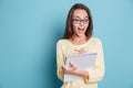 Surprised young woman looking documents over blue background Royalty Free Stock Photo