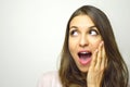 Surprised young woman looking to the side with open mouth with hand on the face on white background. Excited girl looking to the s Royalty Free Stock Photo