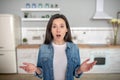 Surprised young woman standing in her kitchen