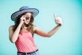 Surprised young woman takes a selfie, funny face, grimace. The girl wore a hat