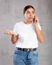 Surprised young woman talking on mobile phone