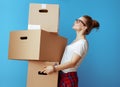 Woman holding pile of cardboard boxes and looking up on blue Royalty Free Stock Photo
