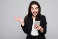 Shocking message. Surprised youngwoman holding mobile phone and staring at it while standing against grey background Royalty Free Stock Photo