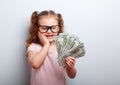 Surprising emotional kid girl holding dollars in hand and thinki Royalty Free Stock Photo