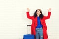 Surprising girl before traveling. Excited young caucasian woman dressed in red coat and hat with suitcase. Woman ready for trip, i