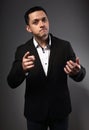 Surprising  grimacing man looking in black suit with funny face showing the finger on grey studio background. Closeup Royalty Free Stock Photo