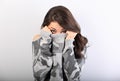 Surprising scared woman with big open eyes hiding her face inside the grey warm winter pullover on blue background Royalty Free Stock Photo