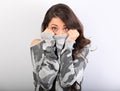 Surprising woman with big open eyes hiding her face inside the grey warm winter pullover on blue background. Closeup Royalty Free Stock Photo