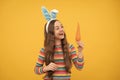 surprisingly tasty. adorable funny kid with carrot. easter spring holiday. surprised teen girl Royalty Free Stock Photo