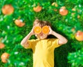 Surprized child holding slices of orange fruit like sunglasses