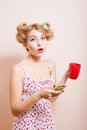 Surprized sexi pinup lady in curlers with cup and