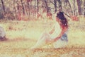 Surreal blurred background of young woman sitting on the stone in forest. abstract and dreamy concept. image is textured and retro