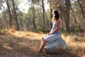 Surreal blurred background of young woman sitting on the tsone in forest