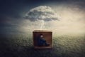 Surreal concept with a scared guy shelters inside a cardboard box. Introvert man caged by own fears as a thunderstorm cloud Royalty Free Stock Photo